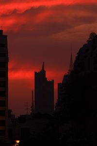 Silhouette buildings against dramatic sky during sunset