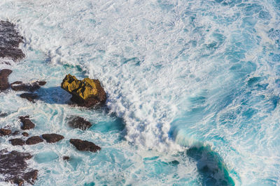 High angle view of wave splashing at rocky shore