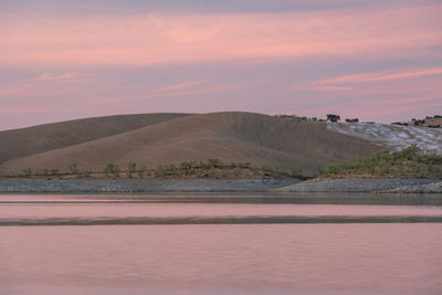 Desert like hill landscape with reflection on the water on a dam lake reservoir in terena, portugal