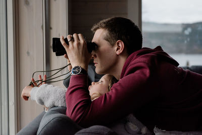 Father and daughter looking through binoculars at the snowy view