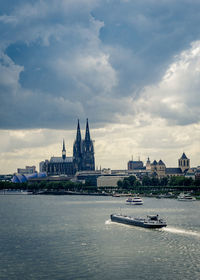 Bridge over river in city against cloudy sky