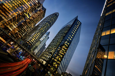 Low angle view of illuminated skyscrapers against blue sky