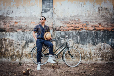 Man riding bicycle leaning against wall