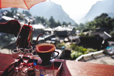 Cropped hand of person pouring water from teapot at table