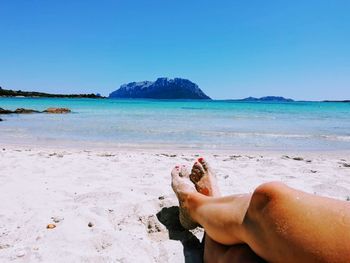 Low section of person on beach against clear sky