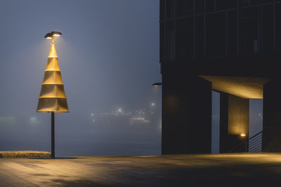 Illuminated street light against building at night