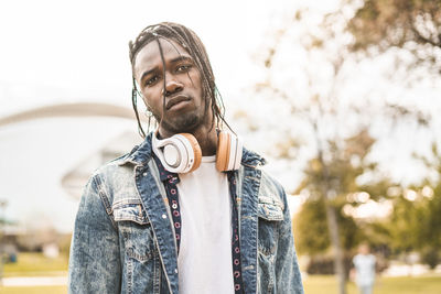 Portrait of young man standing against tree