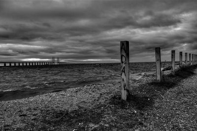 Wooden posts on beach against sky