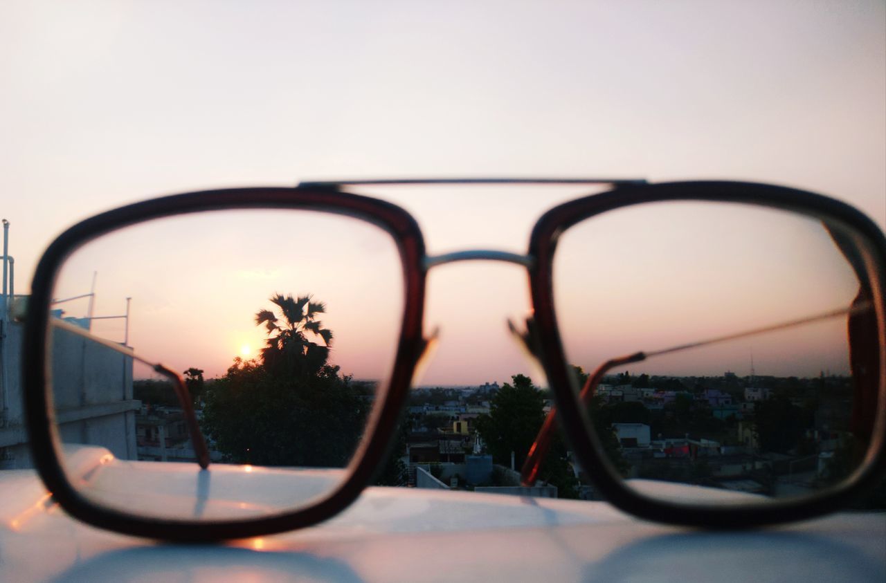 CLOSE-UP OF SUNGLASSES ON SIDE-VIEW MIRROR AGAINST SKY