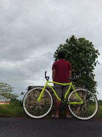 Rear view of man with bicycle against sky