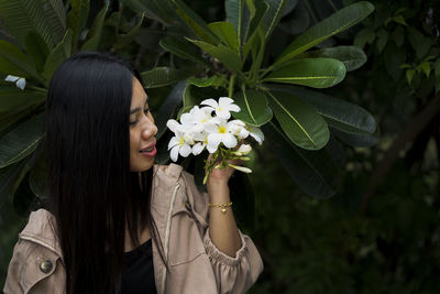 Midsection of woman by flowering plants