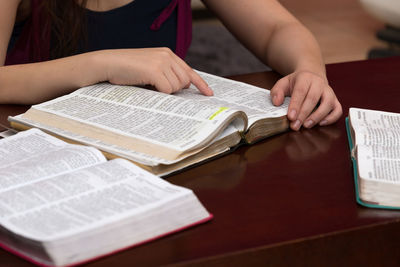 Midsection of woman reading book on table