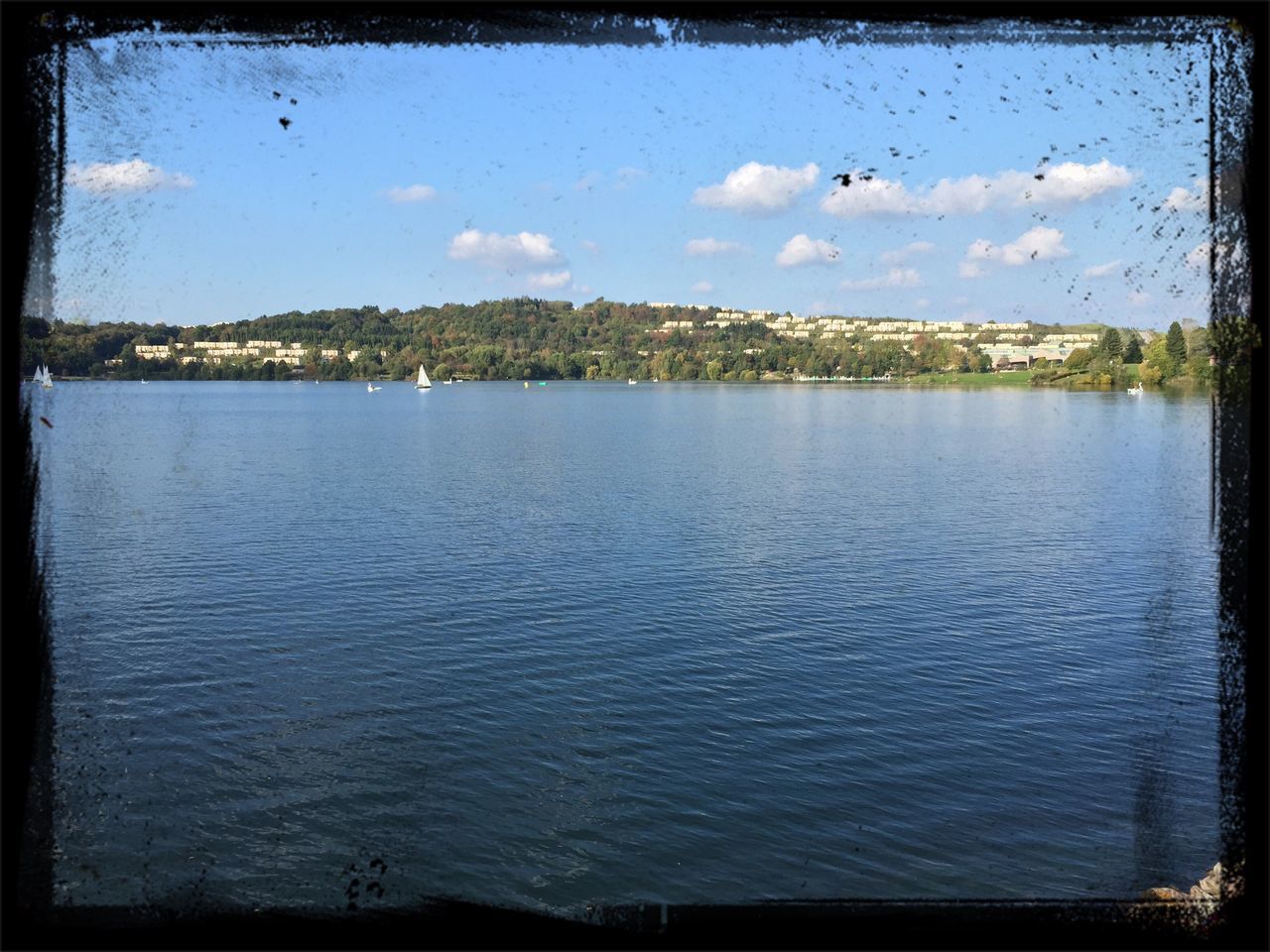 transfer print, water, auto post production filter, sky, waterfront, tranquil scene, bird, tranquility, scenics, lake, cloud - sky, nature, cloud, building exterior, rippled, river, beauty in nature, reflection, sea, built structure