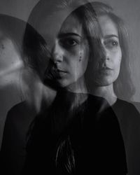 Close-up portrait of young woman against black background