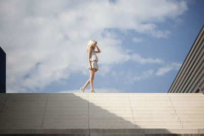 Low angle view of woman walking on steps against sky