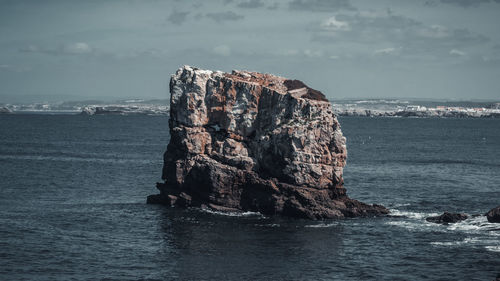 Rock formation on sea against sky