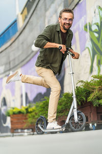 Low section of man riding push scooter on street