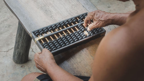 Midsection of shirtless man playing with abacus