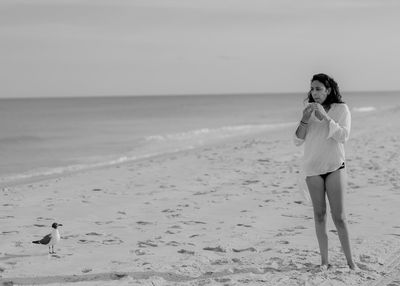 Woman standing on beach against sky