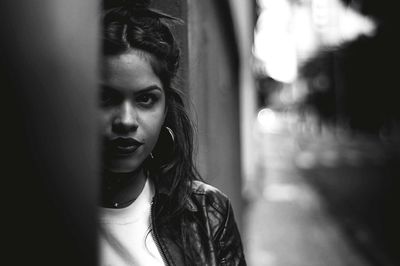 Portrait of young woman standing by wall