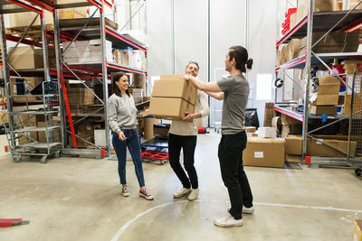 Coworkers assisting man in carrying boxes at distribution warehouse