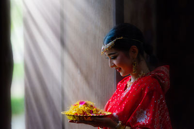 Woman wearing sari holding flowers in plate