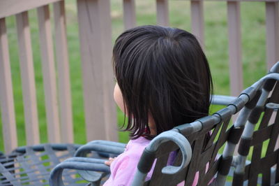 Rear view portrait of a girl sitting in chair