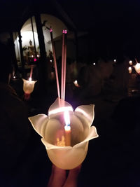 Close-up of hand holding lit candle