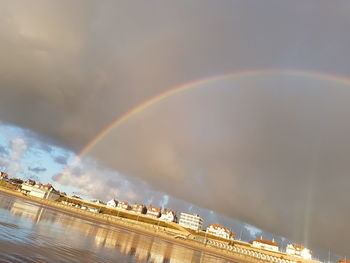Rainbow over buildings in city against sky