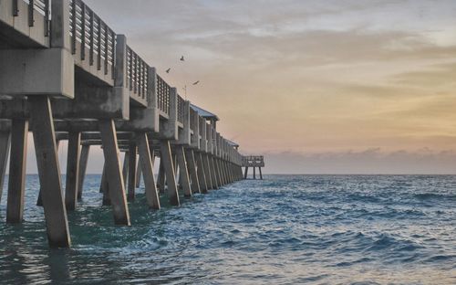 Low angle view of bridge over sea against sky at dusk