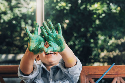 Smilig boy showing messy hands over face