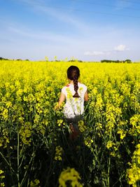 Girl standing amidst yellow flowering plants