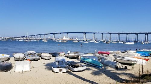 Boats moored in sea against clear blue sky