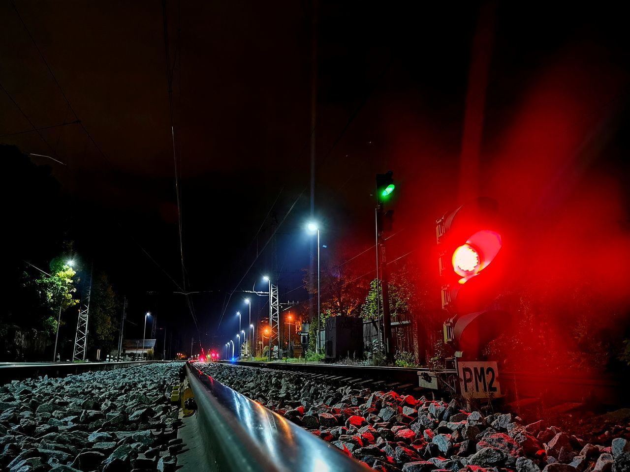 ILLUMINATED RAILROAD TRACKS ON STREET AT NIGHT DURING RAINY SEASON