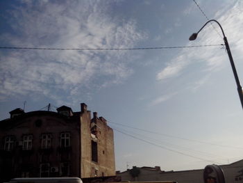 Low angle view of power lines against cloudy sky