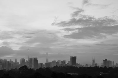 Buildings in city against cloudy sky