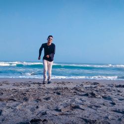 Full length of man standing on beach against sky