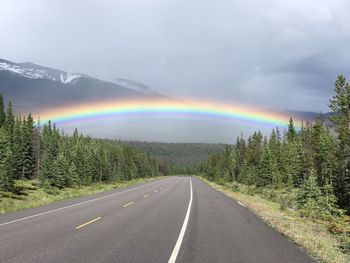 Rainbow over road against sky