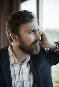 Thoughtful businessman leaning on window in hotel