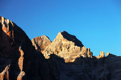 Panoramic view of rocky mountains against clear blue sky