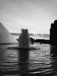 Splashing fountain in pond at musee du louvre against sky