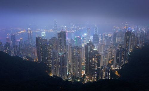 Modern illuminated buildings against sky at night