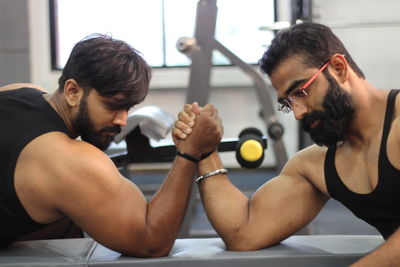 Male friends arm wrestling at gym