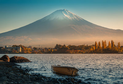 Scenic view of lake and snowcapped mt fuji against clear sky during sunset