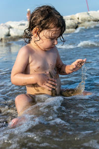 Full length of shirtless boy splashing water