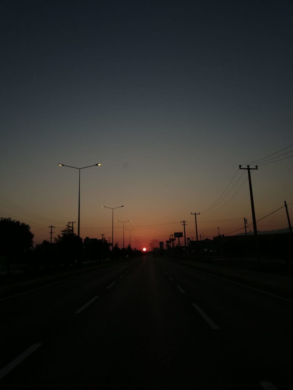 sky, sunset, transportation, street, road, street light, silhouette, nature, no people, motor vehicle, car, the way forward, lighting equipment, city, direction, mode of transportation, sign, highway, orange color, land vehicle, diminishing perspective, outdoors