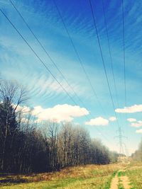 Electricity pylon on field against cloudy sky