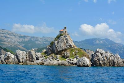 Scenic view of sea by mountain against sky