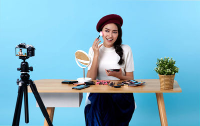Young woman photographing while sitting on table