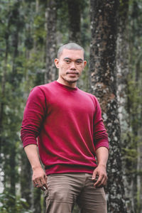 Portrait of mid adult man standing against trees in forest